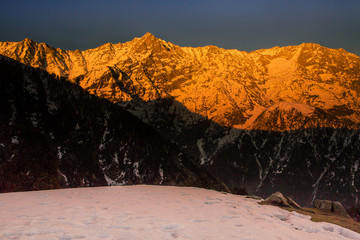 White snow mountains turned golden due to suns rays at golden hour or sunset at Triund, Mcleod ganj, Dharamsala, himachal pradesh, India. Mind blowing scene. golden mountains, hills, camping, dusk © VIVEK