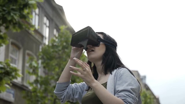 Pretty teenage girl astonished testing a virtual reality headset googles outdoor