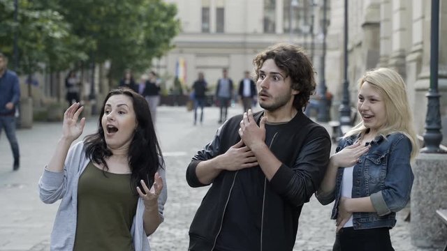 Teenagers friends talking outdoor in public urban street surprisingly having a scared reaction
