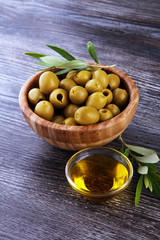 Bottle virgin olive oil and oil in a bowl with some olives