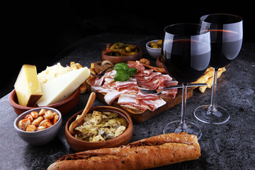 Italian antipasti wine snacks set. Cheese variety, Mediterranean olives, pickles, Prosciutto di Parma, tomatoes, artichokes and wine in glasses