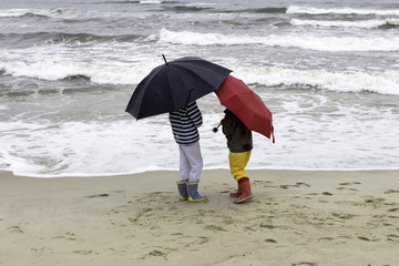 dzieci na plaży w czasie deszczu