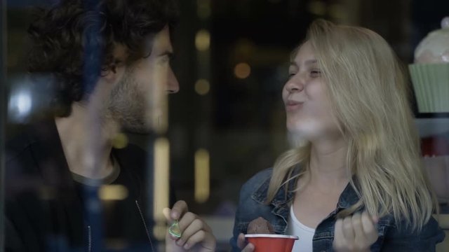 Young couple feeding each other delicious ice cream in a restaurant cafe
