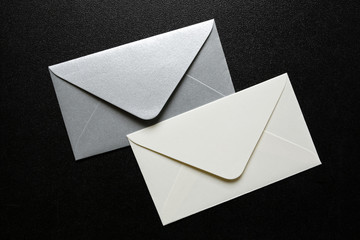 white and silver envelopes on black background