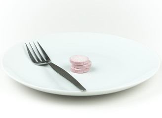 Three food supplement tablets with fork on a white plate