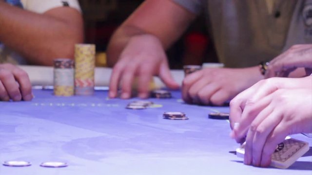 Croupier shuffling cards on poker table.