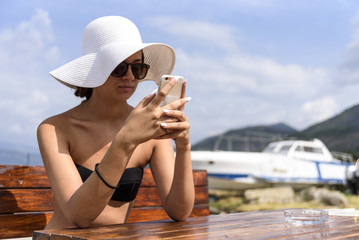 A girl typing a message on a mobile phone on the seashore