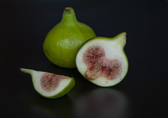 Fresh whole and cut figs on dark background