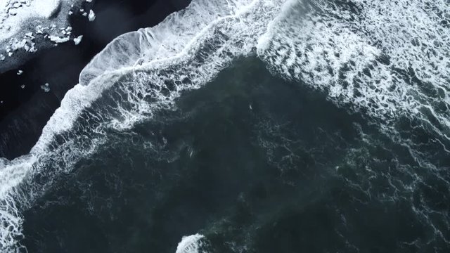 Waves break on snowy shore, Iceland aerial