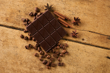 Coffee beans and cinnamon on a old rustic wooden background. Roasted arabica coffee beans pile with cinnamon stick and anise spice ingredients for fragrant coffee.