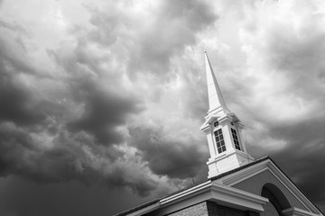 Black and White Church Steeple Tower Below Ominous Stormy Thunderstorm Clouds.
