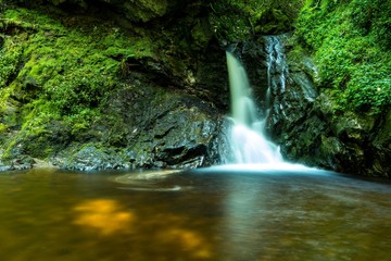 Fototapeta na wymiar Fantasy fairy tail water fall silky green moss jungle tropical water stream