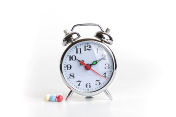 Medicines and alarm clock on white background.