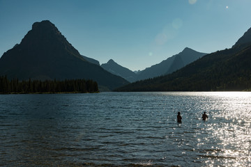 Late afternoon view of Two Medicine Lake in Glacier National Park with swimmers and lens flare