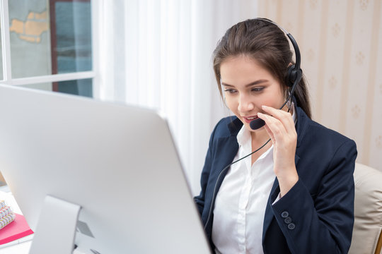 Young beautiful girl working at a laptop in a small medium enterprise. She is operating the phones and computer