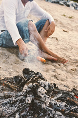 Evening picnic sausages barbeque with bonfire at the seacoast sand
