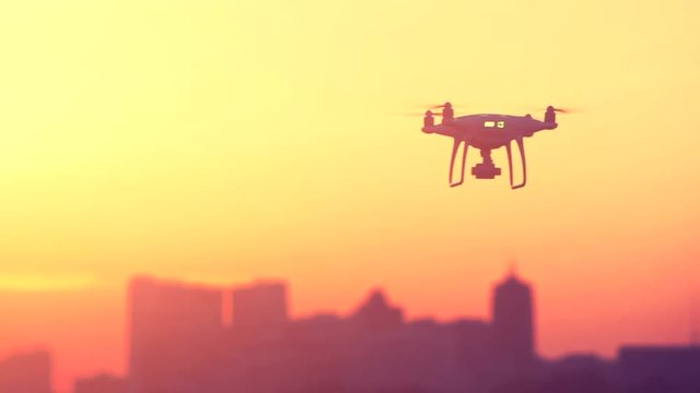 Two Professional Remote Control Air Drones with action cameras flying in dramatic sunset sky. Modern technologies. Travel, hobby, inspiration. Pastel orange toning. Cityscape background. Kiev, Ukraine