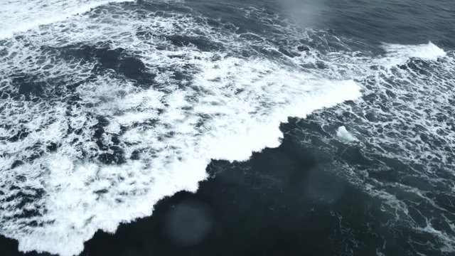 Overhead shot, waves break on Iceland waters