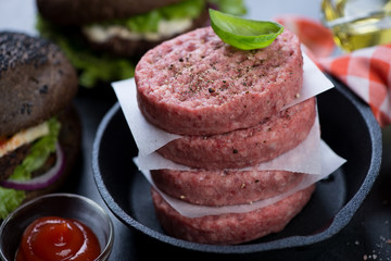 Frying pan with a stack of raw fresh beef burger cutlets, close-up, shallow depth of field