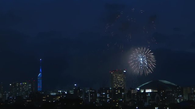 Colorful fireworks exploring in the sky of illuminated urban Fukuoka city.
