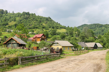 Fototapeta na wymiar Rural houses on slope of forested mountains. Carpathians, Ukraine