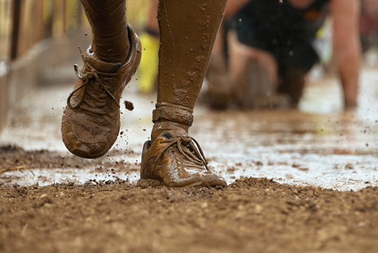 Mud race runners passing under a barbed wire obstacles during extreme obstacle race,detail of the legs