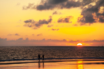 Paar geht am Strand entlang bei Sonnenuntergang am Atlantik