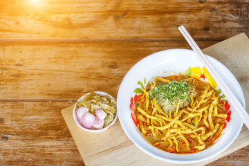 Curried noodle soup (Khao soi) with chicken meat and spicy coconut milk on wood table. Thai food cuisine northern style in Chiang Mai, Thailand.