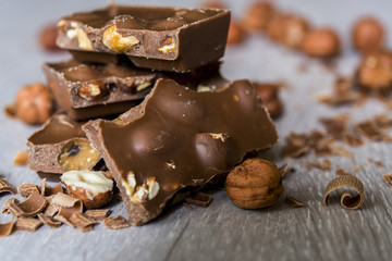 Broken chocolate bar with chips and whole hazelnuts  background texture