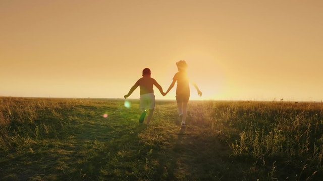 Two carefree children - a girl and a boy of six years running together up the hill. Holding hands. Concept - a happy childhood