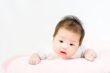 Portrait of a little adorable infant baby girl lying on the tummy on the pillow