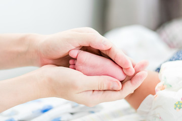 Obraz na płótnie Canvas Baby feet in mother hands againt blurred background