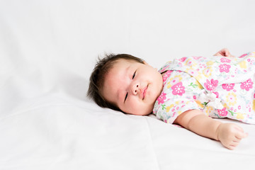 Portrait of a little adorable infant baby girl lying on the back on the bed