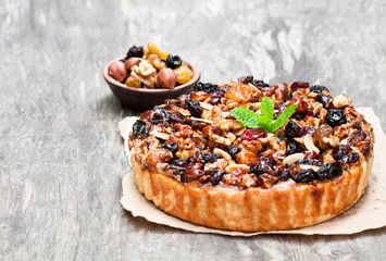 Delicious  tart with dried berries and nuts on old wooden table