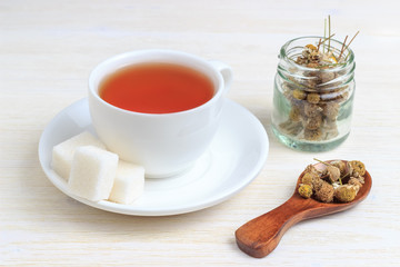 Tea in a cup with a sugar cube and a wooden spoon