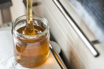 Beekeeper filling up the fresh golden new honey into glass jars