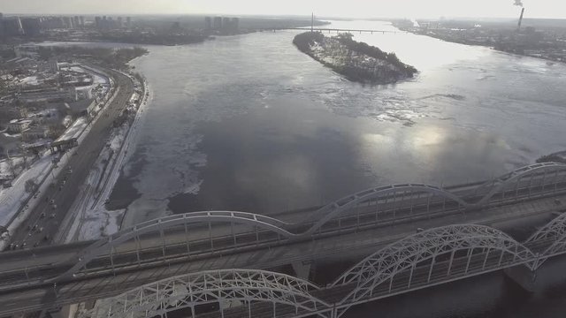 Aerial view city in spring season. Nature landscape with bridge over river. On the water float ice floes.