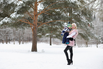 Young mother walks on a winter day with a baby in her arms in the park