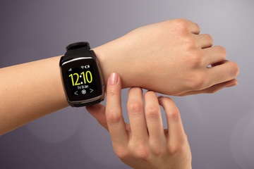 Fototapeta premium Female hand wearing and pressing smartwatch