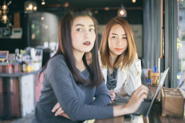 Two Asian business women using notebook working and Discussion of the important contract at office ,soft focus