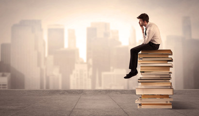 Man sitting on books in the city