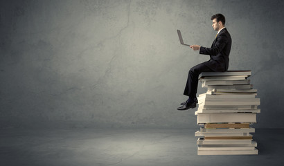 Student sitting on pile of books