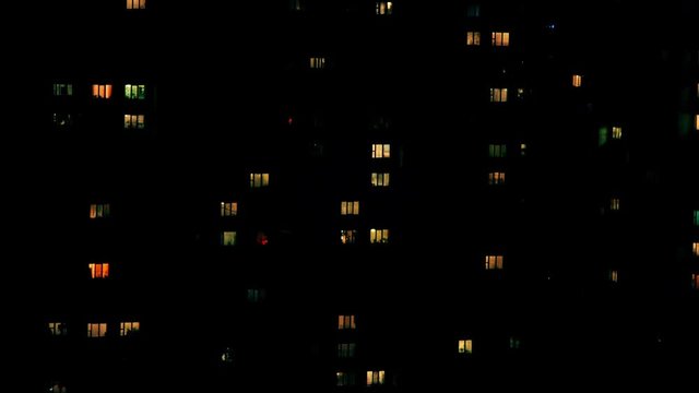 Windows of city building illuminated at night, timelapse 4K video.