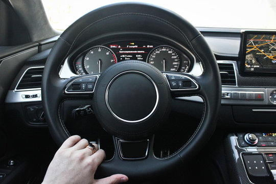 A man holds the steering wheel of a luxury car.