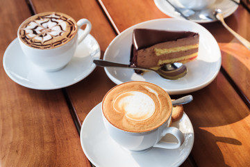 Two cups of hot Cappuccino coffee and chocolate mousse cake