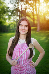 Young housewife with spoon in a natural environment