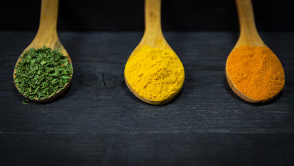 Spices in wooden spoons at the wooden background