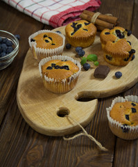 Muffins with blueberries, chocolate and cinnamon on a wooden board