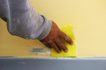 Work plasterer processes the wall of the house with sandpaper. Elimination of poor-quality work...