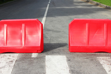 Two red plastic barriers are blocking the road.